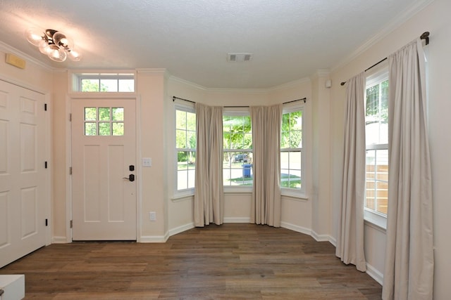 interior space featuring crown molding, baseboards, wood finished floors, and visible vents