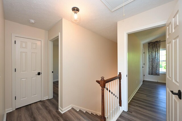 hall featuring baseboards, an upstairs landing, dark wood finished floors, and attic access