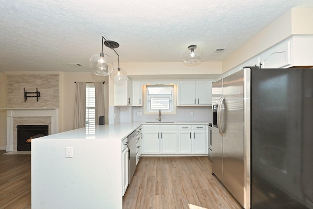 kitchen featuring a textured ceiling, visible vents, appliances with stainless steel finishes, a sink, and a peninsula