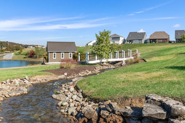 view of yard featuring fence, an outdoor structure, and a water view