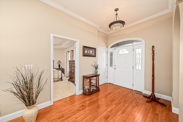 entryway featuring baseboards, ornamental molding, and light wood-style flooring
