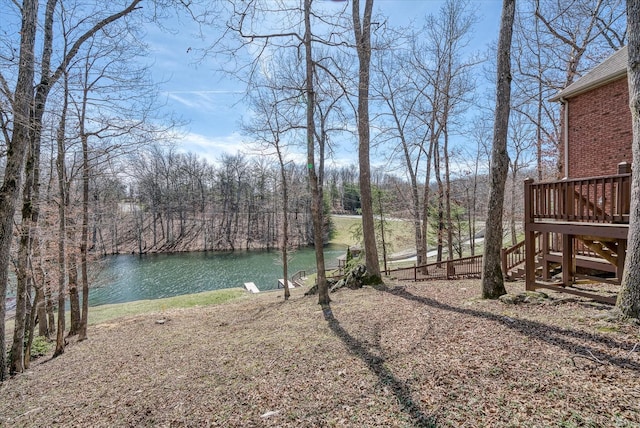 view of yard with stairway and a deck with water view