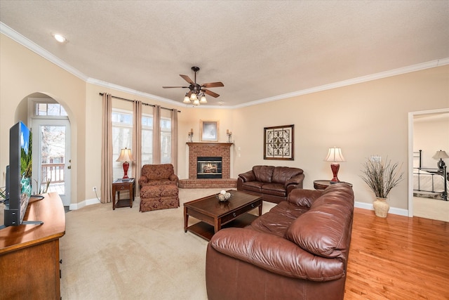 living area with crown molding, a textured ceiling, ceiling fan, and a fireplace