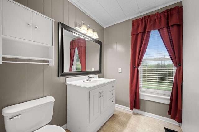 bathroom featuring vanity, a decorative wall, and toilet