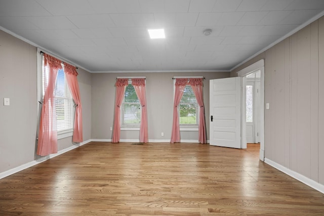 unfurnished room featuring crown molding, baseboards, and light wood finished floors