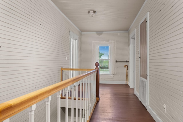 hall with wood walls, dark wood-style floors, and an upstairs landing
