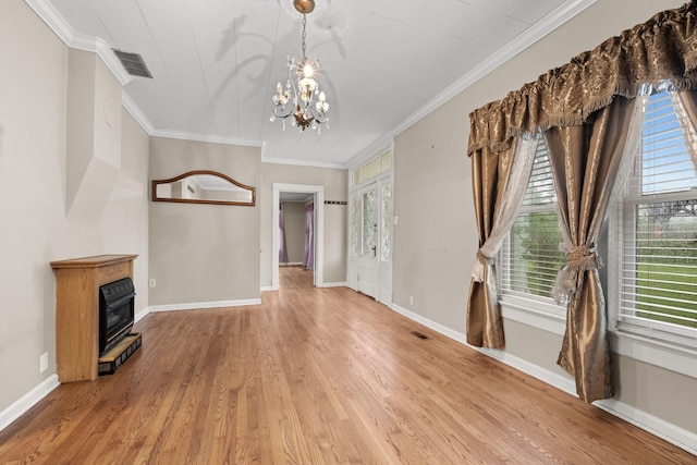 unfurnished living room with a chandelier, baseboards, wood finished floors, visible vents, and ornamental molding