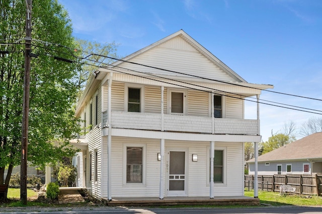 view of front of home featuring a balcony, fence, and covered porch