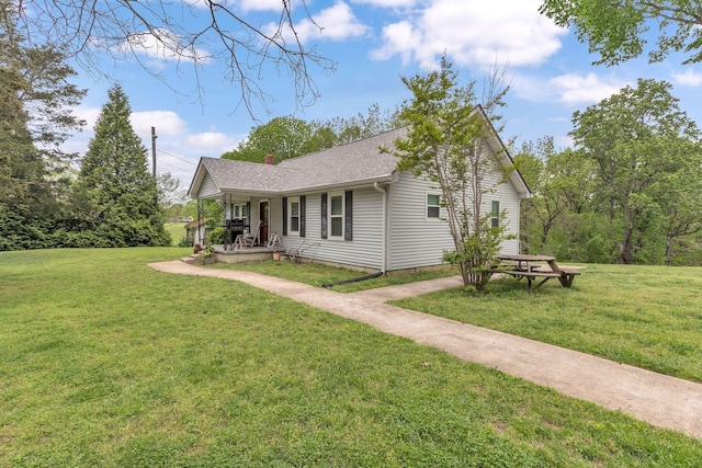 view of front of house featuring a porch, a chimney, a shingled roof, and a front yard