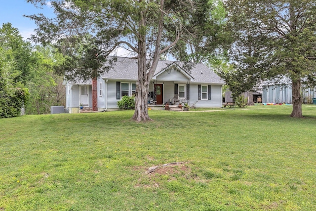 ranch-style home with roof with shingles, central AC unit, covered porch, and a front yard
