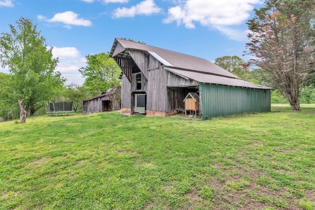 view of barn featuring a yard and a trampoline