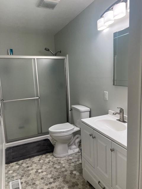bathroom with visible vents, a stall shower, and vanity
