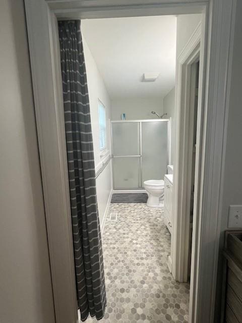 full bathroom featuring toilet, a shower with door, and vanity