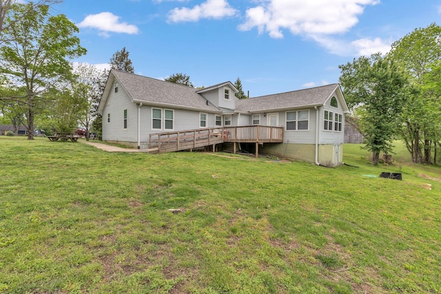 back of property featuring a lawn, roof with shingles, and a deck