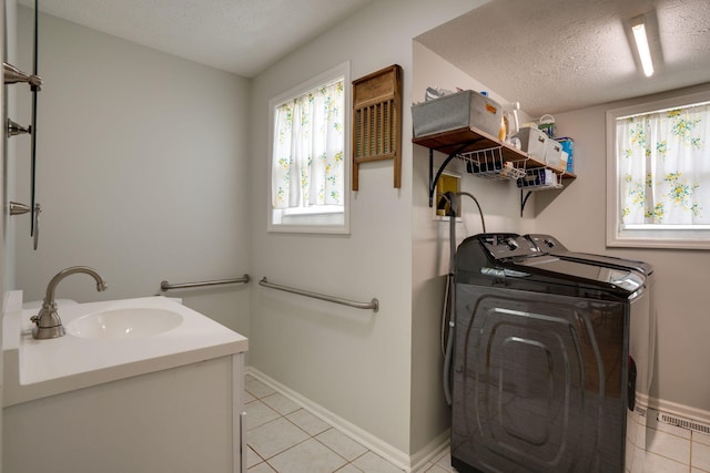 washroom with separate washer and dryer, baseboards, light tile patterned floors, and a sink