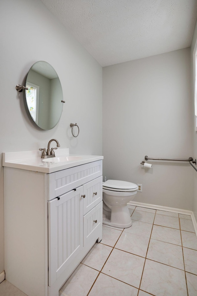 half bath with vanity, toilet, tile patterned floors, a textured ceiling, and baseboards