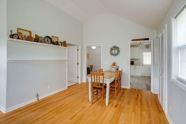 dining area with light wood-type flooring, a ceiling fan, a wealth of natural light, and high vaulted ceiling