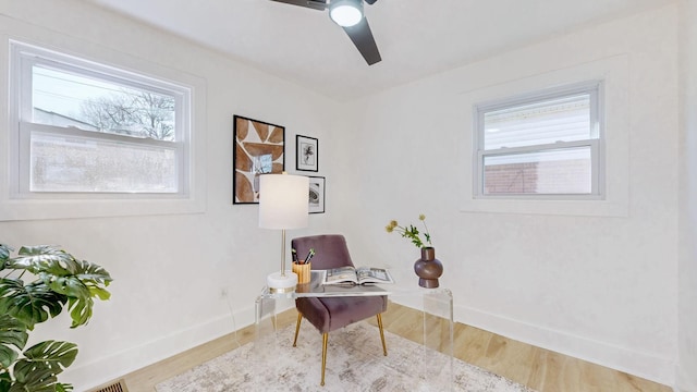 living area featuring baseboards, ceiling fan, and wood finished floors