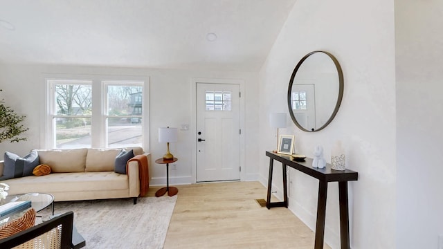 foyer with baseboards, light wood-style flooring, and lofted ceiling