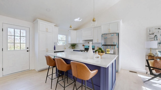 kitchen featuring freestanding refrigerator, electric range, light countertops, white cabinetry, and light wood-style flooring