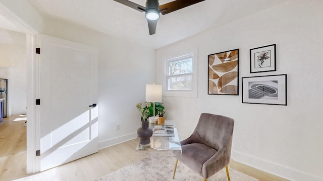 living area featuring baseboards, ceiling fan, and wood finished floors