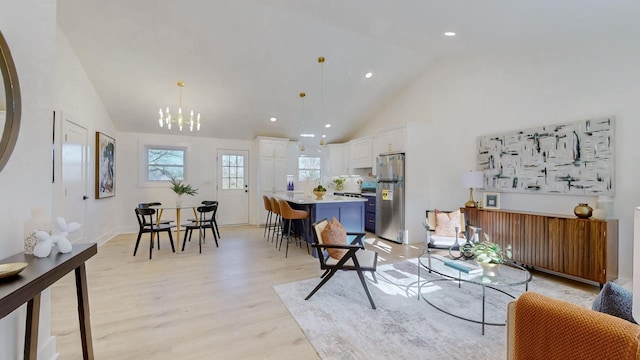 living area featuring recessed lighting, high vaulted ceiling, an inviting chandelier, and light wood finished floors