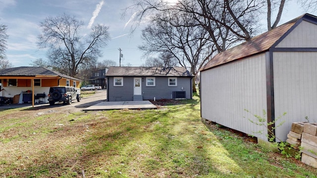 back of house with a lawn, an outbuilding, central AC, and a residential view