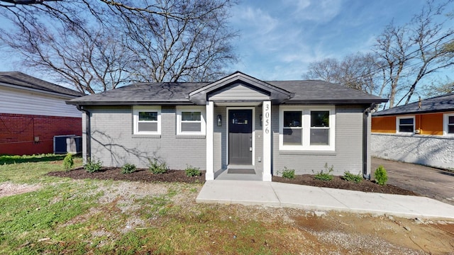 bungalow-style home featuring brick siding, central AC, and a front lawn
