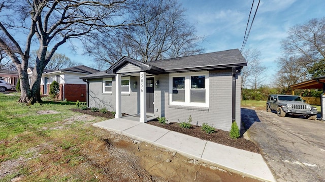 bungalow-style home with a shingled roof, driveway, and brick siding