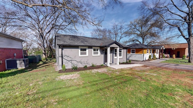 view of front facade featuring brick siding, central AC unit, and a front lawn