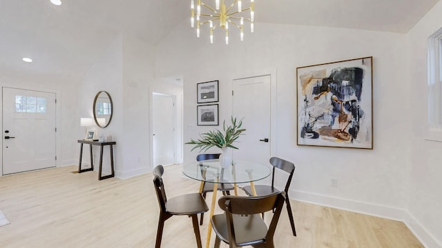 dining area with baseboards, a notable chandelier, lofted ceiling, and light wood-style floors