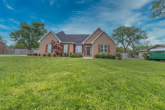 ranch-style house featuring fence, a front yard, and brick siding