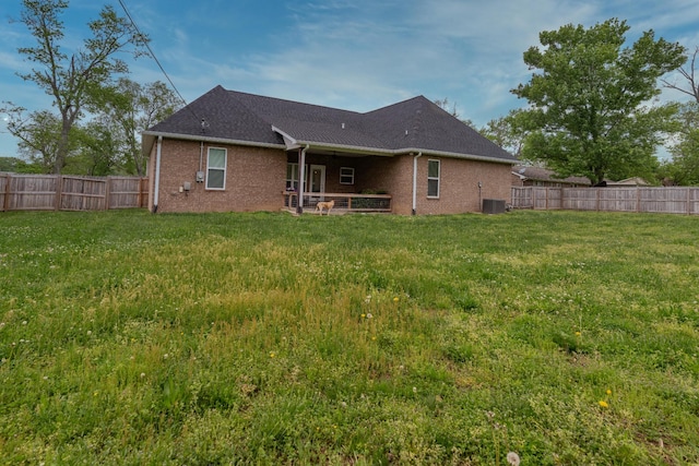 back of property featuring a yard, brick siding, central AC, and a fenced backyard
