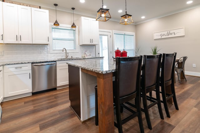 kitchen with a sink, a kitchen breakfast bar, tasteful backsplash, stainless steel dishwasher, and a kitchen island