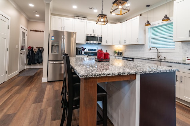 kitchen featuring visible vents, a kitchen bar, a center island, a sink, and stainless steel appliances