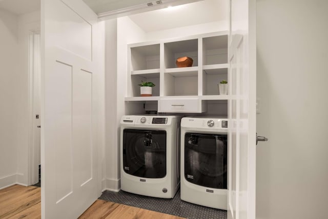 clothes washing area with light wood-style floors, separate washer and dryer, and laundry area