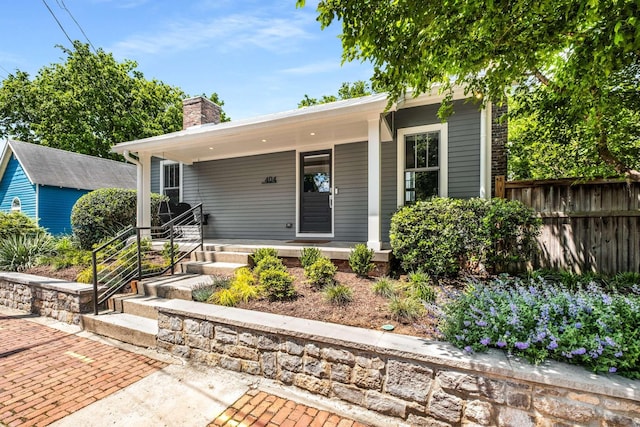 bungalow with fence, covered porch, and a chimney