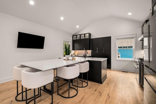 kitchen with high end stainless steel range oven, light countertops, a sink, dark cabinetry, and under cabinet range hood