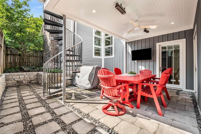 view of patio featuring fence, a ceiling fan, outdoor dining space, and stairway