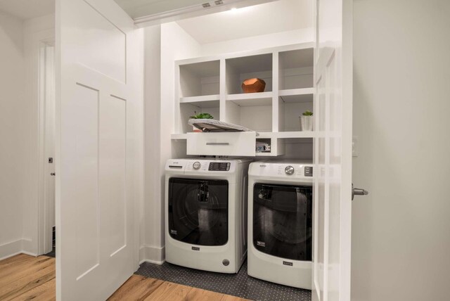 washroom with laundry area, wood finished floors, and washing machine and clothes dryer