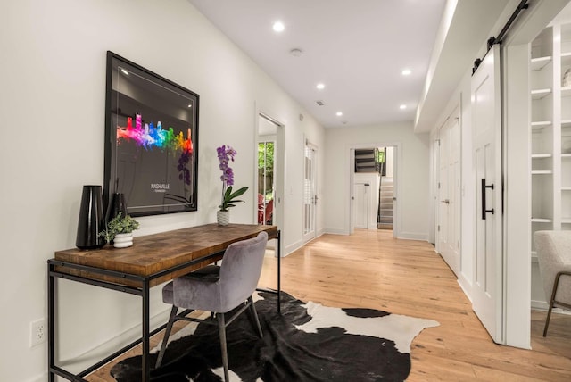home office with recessed lighting, light wood finished floors, and a barn door