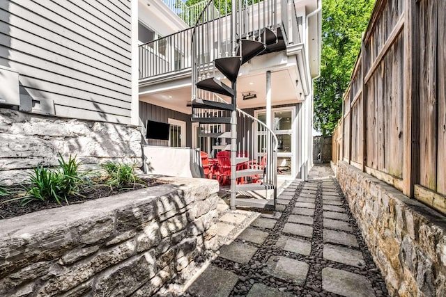 view of patio / terrace with fence, stairs, and a balcony