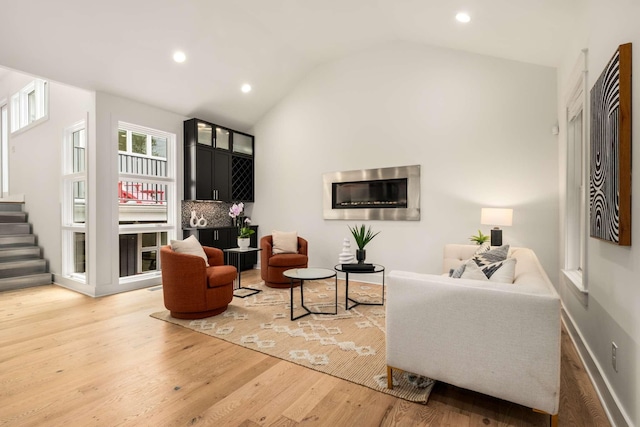 living area with recessed lighting, vaulted ceiling, stairs, and wood finished floors
