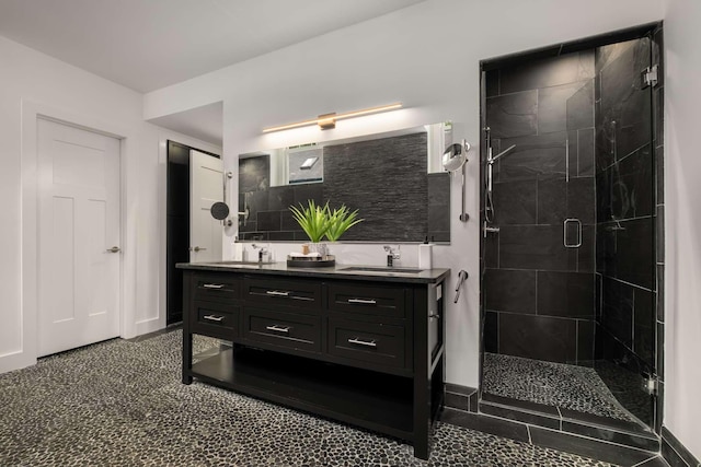 full bathroom featuring double vanity, baseboards, a shower stall, and a sink