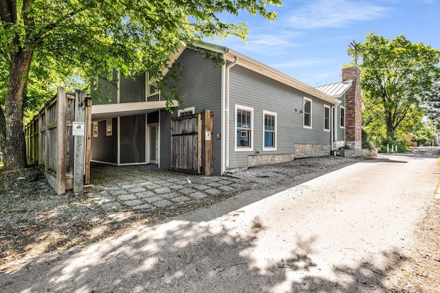 view of side of home with fence, a standing seam roof, a chimney, and metal roof
