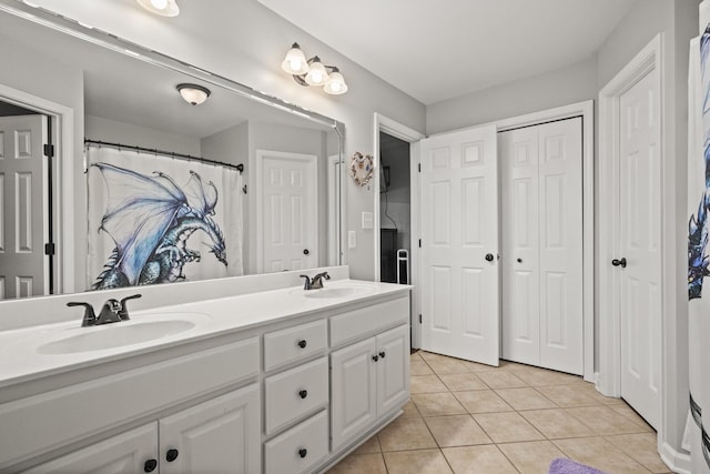 full bath featuring double vanity, a sink, tile patterned flooring, and a closet