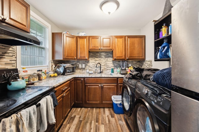 235 Brevard Ct, Nashville, TN 37211 - kitchen featuring backsplash, appliances with stainless steel finishes, washing machine and dryer, light wood-type flooring, and a sink