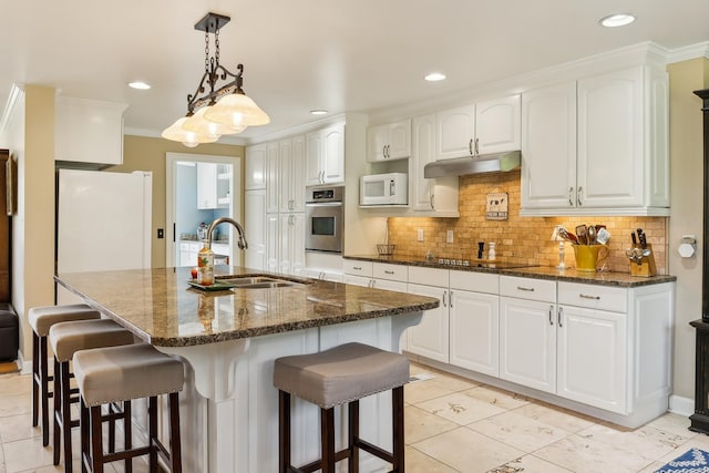 921 Cooks Rd, Mount Juliet, TN 37122 - kitchen featuring white appliances, a breakfast bar area, under cabinet range hood, tasteful backsplash, and a sink