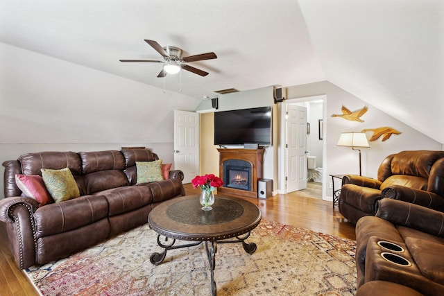 living area with visible vents, a ceiling fan, wood finished floors, and vaulted ceiling