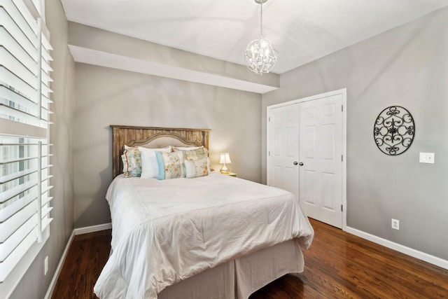 bedroom featuring baseboards, an inviting chandelier, wood finished floors, and a closet